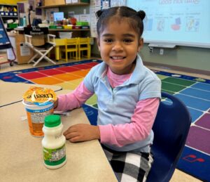 Young female student eating lunch at a table in her classroom