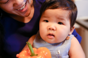 Mother and Baby Holding Orange Pepper