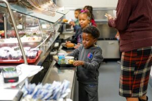 Young boy going through lunch line in a school cafeteria with his tray